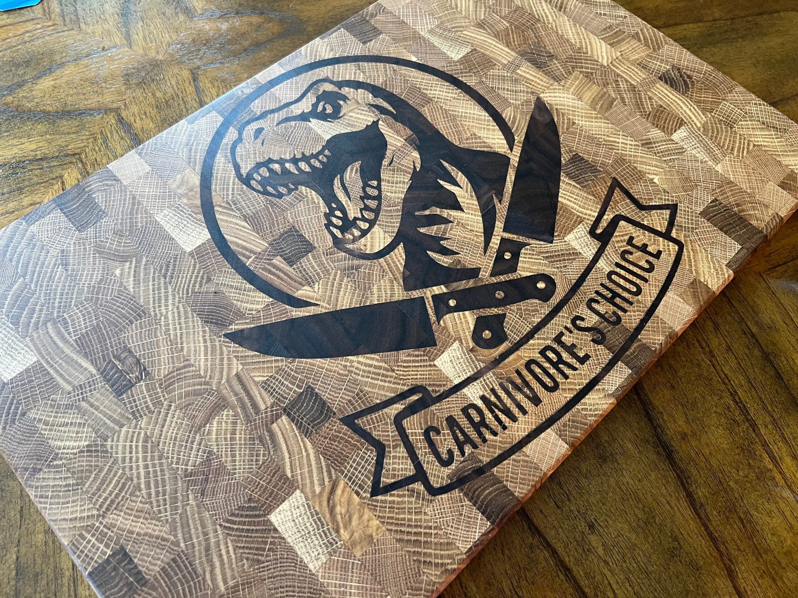 Close-up of Carnivore’s Choice dinosaur engraving on end grain cutting board.