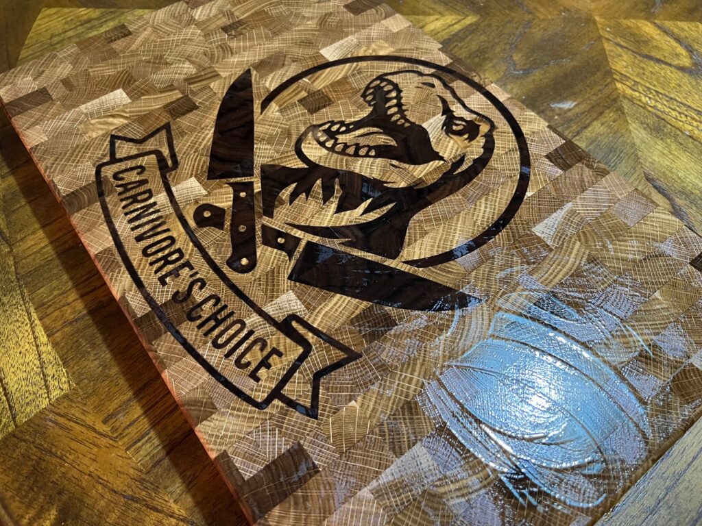 Finished dinosaur end grain cutting board with oil applied, shown from an angled view.